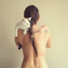 Vista trasera de una mujer desnuda sosteniendo a su gato mascota - foto de stock