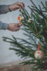 Abgeschnittenes Bild eines Jungen, der einen Weihnachtsbaum schmückt — Stockfoto