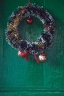 Corona de oropel de Navidad con adornos en una puerta - foto de stock