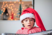 Портрет мальчика, читающего в рождественской шляпе Санты — стоковое фото