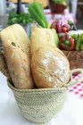 Basket with fresh loafs of bread on table — Stock Photo