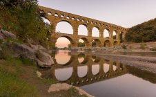 Vue panoramique de l'aqueduc Pont Du Gard reflets dans la rivière gardon, France — Photo de stock