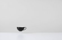Copo de café preto flutuando no ar médio — Fotografia de Stock