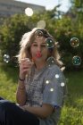 Молодая женщина надувает мыльные пузыри — стоковое фото