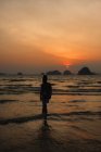 Silhouette di donna in piedi sulla spiaggia al tramonto, Thailandia — Foto stock