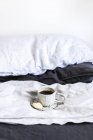 Xícara de chá e um biscoito em uma cama — Fotografia de Stock