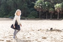 Menina andando ao longo da praia no dia ensolarado — Fotografia de Stock