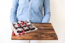 Woman holding chopping board with brownies — Stock Photo