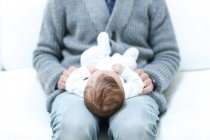 Чоловік сидить на дивані з новонародженою дитиною — стокове фото