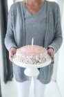 Donna che porta torta di compleanno su uno stand torta — Foto stock