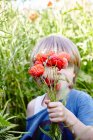 Boy holding a bouquet of poppy flowers in front of his face — Stock Photo