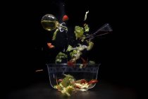 Vista close-up de ingredientes de salada caindo em tigela — Fotografia de Stock