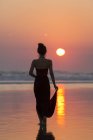 Silhouette of woman in dress on beach, Bali sunset sun in sky — Stock Photo