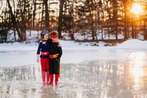 Boy and girl standing on frozen lake wearing superhero costumes — Stock Photo