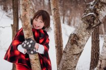 Girl in hooded parka standing amongst trees in winter — Stock Photo