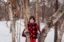 Mädchen im Kapuzenparka steht im Winter zwischen Bäumen — Stockfoto