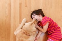Visão aérea do cão retriever dourado lambendo o rosto da menina. — Fotografia de Stock