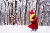 Fille jouer dans les bois dans la neige dans la forêt d'hiver — Photo de stock