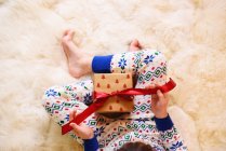 Дівчина сидить на килимі і відкриває різдвяний подарунок — стокове фото
