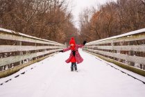 Girl spinning around in snow on a bridge — Stock Photo