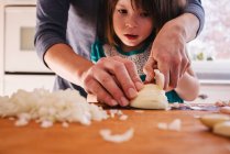 Mother teaching her daughter to chop onions — Stock Photo