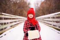 Girl standing on bridge in snow with a fake fur muff — Stock Photo