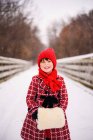 Девушка, стоящая на мосту в снегу с фальшивой меховой муфтой — стоковое фото