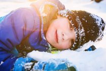 Retrato de un niño sonriente tirado en la nieve - foto de stock