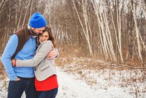 Man and woman standing in snow hugging — Stock Photo