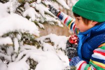 Junge schmückt Weihnachtsbaum im Garten — Stockfoto