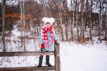 Ragazza in piedi sulla recinzione nella neve — Foto stock