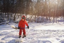 Мальчик убирает снег на лугу зимой — стоковое фото