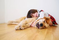 Girl sitting on floor cuddling her dog — Stock Photo