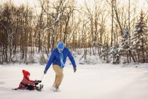 Vater zieht Tochter auf Schlitten in den Schnee — Stockfoto