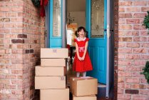 Fille debout près de la porte d'entrée avec livraison de boîtes — Photo de stock