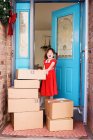 Chica de pie por la puerta principal con la entrega de cajas - foto de stock