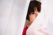 Menina escondida atrás de uma cortina — Fotografia de Stock