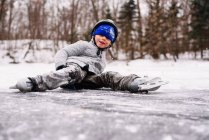 Rapaz patinagem no gelo e cair — Fotografia de Stock