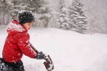 Boy shoveling snow in winter forest — Stock Photo