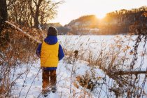 Хлопчик йде вздовж берега річки в снігу — стокове фото