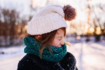 Девушка в качающейся шляпе и шарфе, стоящая в снегу с забавным лицом — стоковое фото