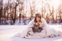 Girl dressed as snow queen sitting in the snow — Stock Photo