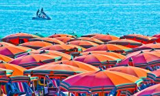Parasols sur la plage avec un bateau au loin, Italie — Photo de stock