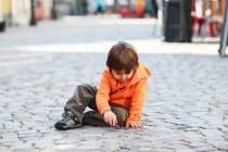 Хлопчик сидить на вулиці, граючи з іграшковою машиною — стокове фото