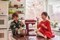 Dos niños ayudando a hornear galletas juntos en la cocina - foto de stock