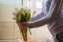 Жінка розставляє тюльпани у вазі, вид зблизька — стокове фото