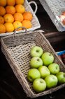 Oranges and apples in baskets at fruit market — Stock Photo