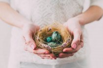 Femme tenant un nid avec des œufs de Pâques — Photo de stock