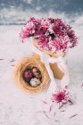Flores cor de rosa em um saco de papel e ovos de Páscoa — Fotografia de Stock