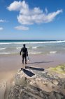Hombre de traje de neopreno de pie en la playa, Los Lances, Tarifa, Cádiz, Andalucía, España - foto de stock